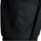 Close-up of the men's coat, showing the contrast between the smooth side pocket and the ribbed knitted texture.
