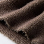 A detailed view of the men's sweater, showing the soft, plush texture of the knit fabric in brown.