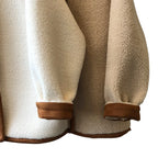 Detailed view of the women's sherpa coat's sleeve and hem, highlighting the contrasting trim and the cozy, reversible material.
